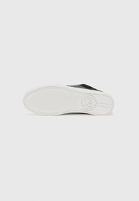 Zwarte sneaker met een gestructureerde leren bovenkant en een witte rubberen zool. Heeft een ronde logo op de zool met een gladde afwerking.