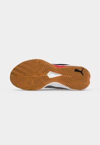 Semelle d'une chaussure de sport avec un motif de bande de roulement en zigzag marron, des accents blancs sur la semelle intermédiaire et un logo Puma noir sur la partie du talon.