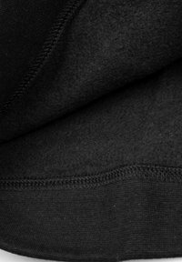 Tissu noir présentant un intérieur doux et texturé, avec une couture plate le long du bord. Le matériau semble chaud et élastique.