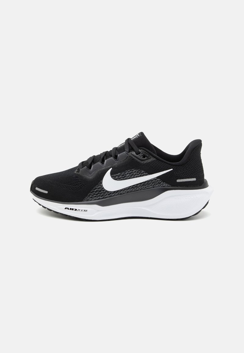 Chaussure de sport noire avec une tige en maille, un logo Nike en blanc et une semelle blanche rembourrée avec des détails texturés.