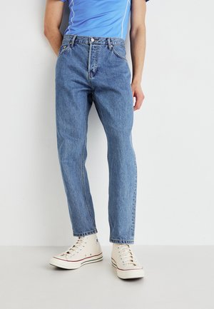 Lysblå denim jeans med lige pasform, fem lommer og klassisk knaplukning, parret med off-white sneakers.