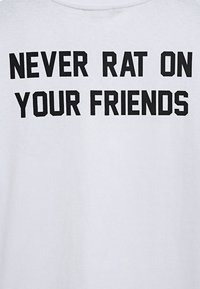 Biała bawełniana koszulka z krótkim rękawem z odważnym czarnym napisem "NIGDY NIE ZDRADZAJ SWOICH PRZYJACIÓŁ". Krój z okrągłym dekoltem i standardowym dopasowaniem.