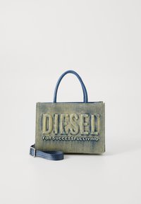 Sac en denim avec le logo "DIESEL" en relief. Forme rectangulaire, de couleur bleue, avec des poignées doubles et une sangle amovible. Fini texturé.
