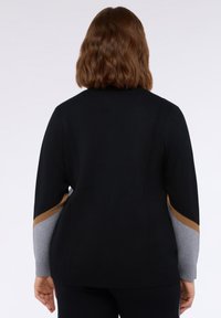 Czarny wełniany kardigan z długimi rękawami, z szaro-brązowymi akcentami w diagonalne kolorowe bloki na rękawach. Miękka tekstura i luźny krój.