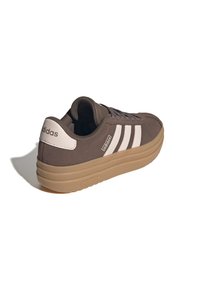 Brown Adidas sneaker with white stripes and a thick light brown sole angled to show back and side details.