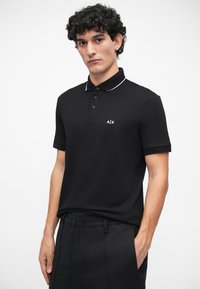 Tricou polo negru, cu o croială slim fit, cu o deschidere cu trei nasturi și detalii ale gulerului în dungi albe; prezintă logo-ul A/X pe pieptul stâng.