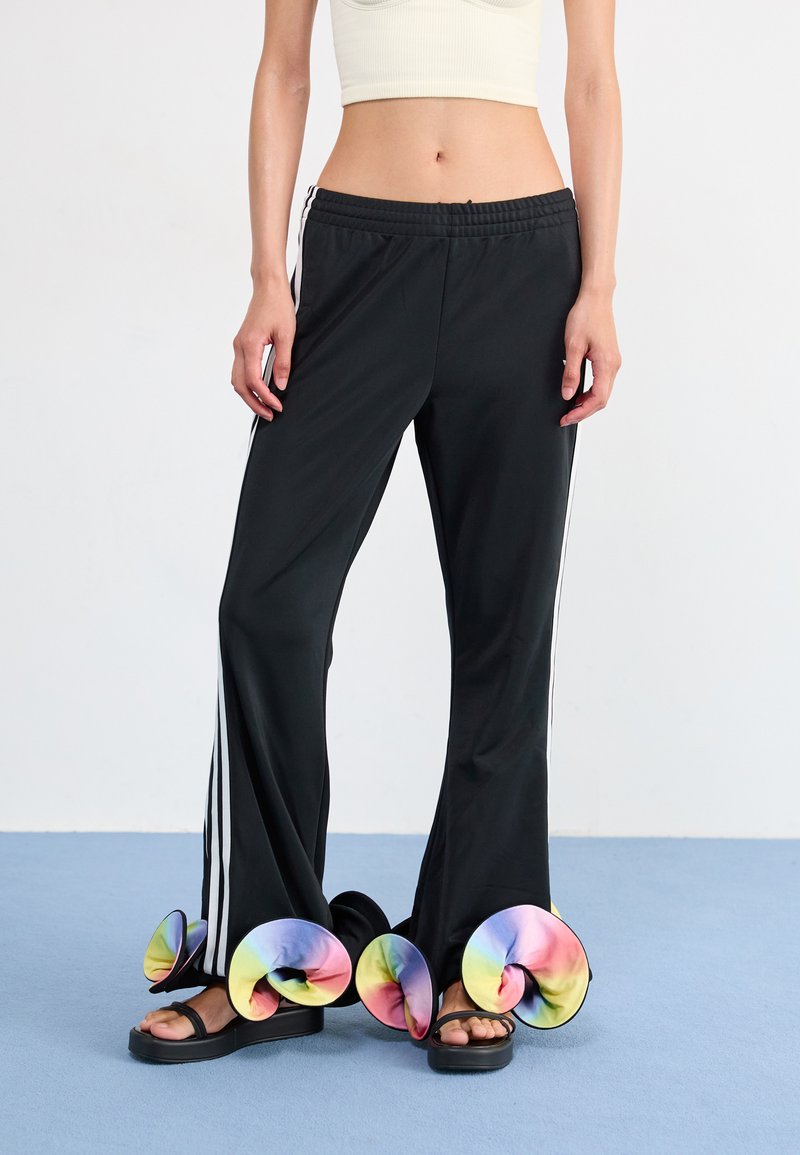 Black athletic pants with white side stripes, paired with unique sandals featuring colorful spiral accents and a thick black sole.