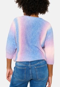 Pletený pulovr se stupňovou barevnou kombinací pastelové modré a růžové, s volným střihem a tříčtvrtečními rukávy. Kombinováno s modrými džíny.