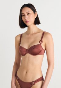 Hnědý bikinový komplet se strukturovaným podprsenkovým topem s kulatými kovovými detaily a nastavitelnými ramínky; odpovídající kalhotky s nízkým pasem se stejným zdobením.