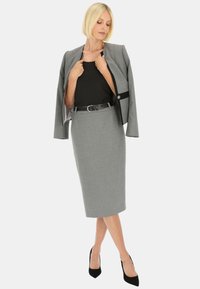 Szary żakiet o dopasowanym kroju z czarnymi akcentami, zestawiony z szarym ołówkowym spódnicą. Czarny pasek, wysokie obcasy, elegancki design, gładka tekstura.