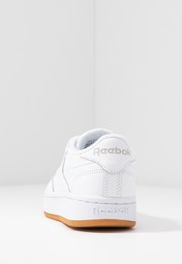 Vita lädersneakers med vadderad krage, slät textur, förstärkt sömnad och tanfärgad gummisula. "Reebok"-logotyp i silver på hälen.