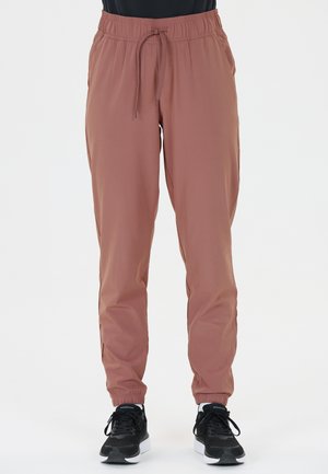 Lätta, dammiga rosafärgade joggerbyxor med elastisk midja, dragsko, sidofickor och avslutade anklar. Kombinerade med svarta sneakers.