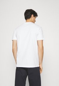 White cotton T-shirt with a crew neckline and short sleeves, displayed from the back, featuring a relaxed fit and smooth texture.