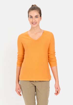 Oranje V-hals langemouwtop met geribde textuur; casual pasvorm; gecombineerd met lichtbeige broeken.