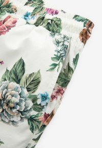 Tessuto a patterned floreale con base bianca. Presenta vari toni di fiori rosa, blu e verdi, con una vita elastica arricciata.