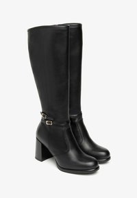 Schwarze Lederkniehohe Stiefel mit einem klobigen Absatz, seitlichem Reißverschluss, dekorativen Schnallen und glatter Textur.