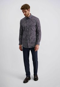 Herren Langarmhemd mit dunkellila Grundfarbe und weißem Blumenmuster. Kombiniert mit navyfarbigen Slim-fit-Hosen und dunklen Lederschuhen.