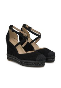 Chaussures à talons compensés en suede noir avec des sangles croisées, un bout arrondi et des accents décoratifs en perles sur la plateforme. Texture douce et design robuste.