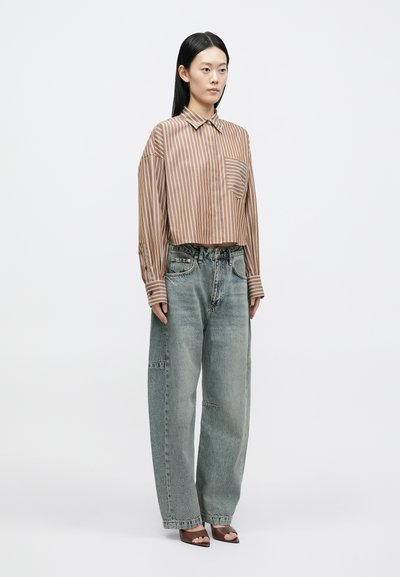 Pruunide triipudega pikkade varrukatega triiksärk rinnataskuga, kombineeritud helesiniste üleliigsete teksapükstega. Modell kannab pruune kontsaga sandaale.