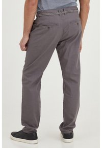 Grå bomullsbukser med rak skärning, två bakfickor och ett flätat skärp. Matchas med svarta sneakers.