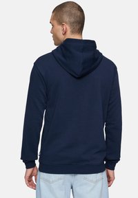 Sudadera azul marino con capucha ajustable, puños y dobladillo acanalados; textura suave; diseño liso. Solo es visible la vista trasera.