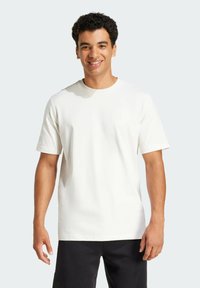 Hvid bomulds T-shirt med korte ærmer, prydet med et subtilt logo på brystet. Glat tekstur, standard rund halskrave og afslappet pasform.