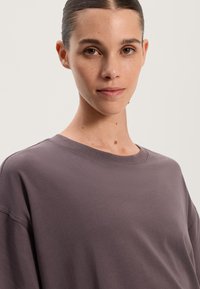 Oversized t-shirt med rund hals i en dämpad mauve-färg. Mjukt bomullsmaterial med korta ärmar och en slät, enfärgad yta.