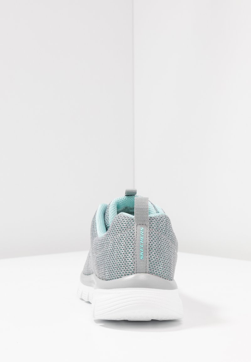 Zapatilla de malla gris con acentos turquesa, que cuenta con una pestaña de tiro y un talón texturizado. Suela ligera con dibujo en relieve para mayor tracción.