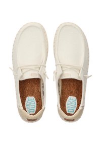Baskets en toile blanches avec un dessus texturé, semelle intérieure en liège, talon en cuir contrastant et une légère couture autour de la semelle.