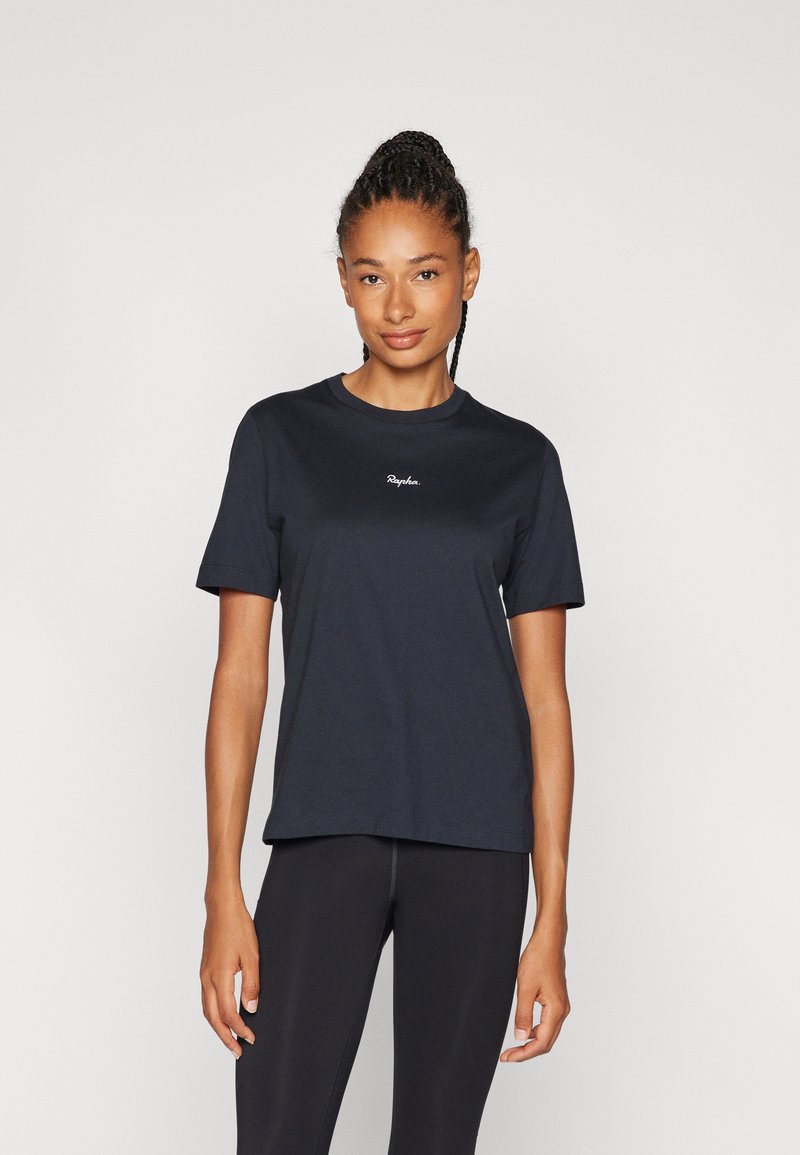 Schwarzes Baumwoll-T-Shirt mit kurzen Ärmeln, Rundhalsausschnitt und gesticktem Logo auf der Brust. Kombiniert mit schwarzen Leggings für einen stimmigen Look.