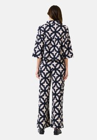 Maritiem en roomkleurig gestreept twee-delig outfit met een cropped shirt met brede mouwen en hoog op de taille zittende, uitlopende broek.
