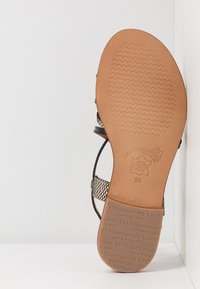 Sandalo nero con un design a strisce intrecciate, suola in gomma marrone con un motivo a zigzag e dettagli del marchio impressi. Taglia 38.