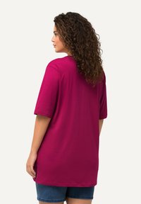 T-shirt overdimensionato fucsia con maniche corte, realizzato in cotone morbido. Caratterizzato da un collo rotondo e spacchi laterali per un comfort aggiuntivo.