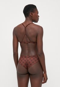 Braunes Lingerie-Set mit floralem Muster auf dem Slip und einem trägerlosen Bralette. Der Stoff ist glatt mit verstellbaren Trägern und Haken.