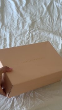 Pfirsichfarbener Karton mit glatter, matter Oberfläche, der geprägt mit goldener Schrift "Loeffler Randall" auf der Oberseite versehen ist. Rechteckige Form.