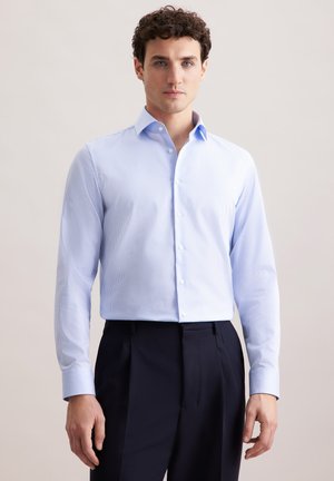 Chemise habillée bleu clair à manches longues avec un motif rayé, boutonnée à l'avant et avec un col. Portée avec un pantalon sombre. Texture de tissu lisse.