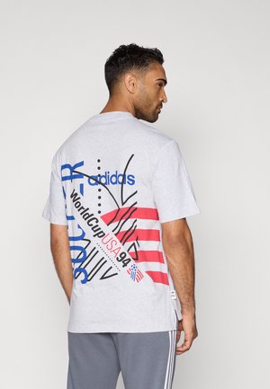 Grijze katoenen t-shirt met een sportief ontwerp en blauwe en rode tekst, strepen en accenten die de Wereldbeker van 1994 vertegenwoordigen.