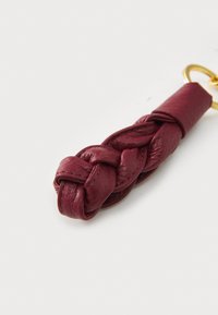 Braided burgundy leather keychain with a smooth texture, featuring a gold-tone metal ring attachment. Accented by a knotted design.