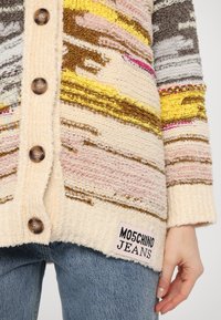 Καρδigan με υφή, πολύχρωμο, με κίτρινες, ροζ και καφέ ρίγες, που διαθέτει σκούρους κουμπιά και λογότυπο "Moschino Jeans" στη γαζωμένη άκρη.