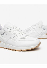 Hvide lædersneakers med perforerede detaljer, teksturerede accenter og en tan gummisål. Har flade snørebånd og en polstret krave.