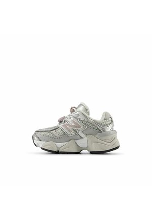 Grijs-witte New Balance sneaker met mesh- en leren bovenwerk, dikke zool en vetersluiting, zijaanzicht tegen een witte achtergrond.