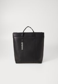 Borsa tote in pelle nera con chiusura a zip, due manici superiori e logo "HUGO" in rilievo sulla parte anteriore. Texture liscia e design strutturato.