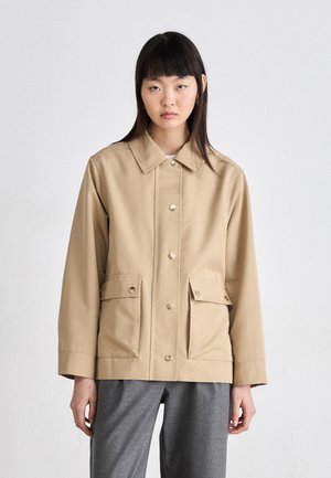 Beige Utility-Jacke mit Kragen, Frontknöpfen und zwei Brusttaschen. Hergestellt aus strapazierfähigem Stoff, mit weiter Passform und geraden Ärmeln.