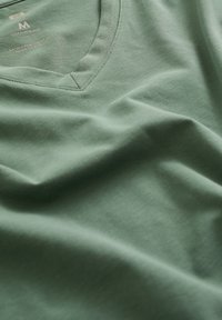 Grøn bomuldsblandet T-shirt med V-hals og blød tekstur. Har et mærke med størrelse 'M' i et minimalisk design.