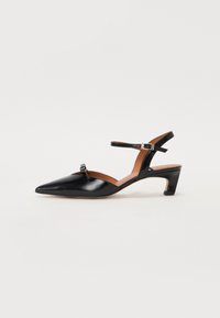 Sorte patentlæder mid-hæle sandal med spids tå, ankelrem og dekorativ sløjfedetail foran. Glat tekstur og minimalistisk design.