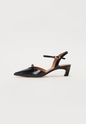 Black patent leather mid-heel sandal with pointed toe, ankle strap, and decorative bow detail on the front. Smooth texture and minimalist design.