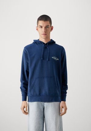 Felpa con cappuccio blu navy realizzata in tessuto morbido, con tasca frontale, cappuccio regolabile con coulisse e un piccolo logo stampato sul petto.
