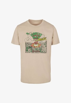 T-shirt en coton beige avec un imprimé graphique comportant un texte vert vif "GREEN DAY", des nuages et des illustrations colorées en dessous.