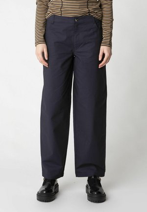 Navy blue trousers with a loose fit, featuring a button closure, two front pockets, and a smooth texture. Paired with black chunky shoes.