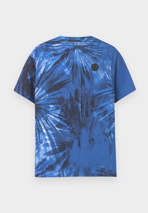 T-shirt bleu à manches courtes avec un imprimé abstrait de feuilles de palmier noires et un petit logo circulaire noir sur la zone de la poitrine gauche.